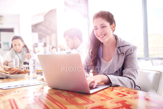 Donna d'affari digitando sul computer portatile durante il pranzo di lavoro nel ristorante — Foto stock