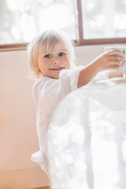 Girl with milk moustache smiling at camera — Stock Photo