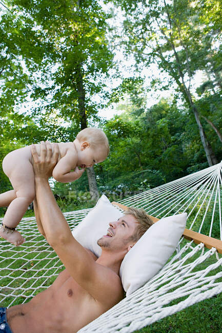 Father on hammock lifting baby daughter — Stock Photo