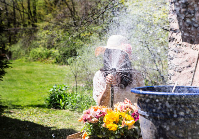 Woman spraying water towards camera — Stock Photo