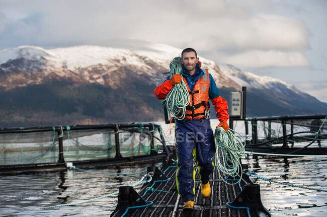 Worker on salmon farm in rural lake — Stock Photo