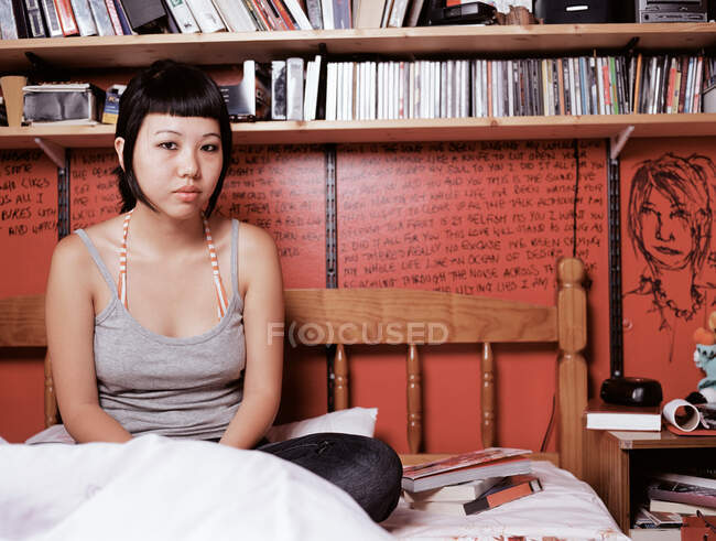 Teenage girl sitting on bed — Stock Photo