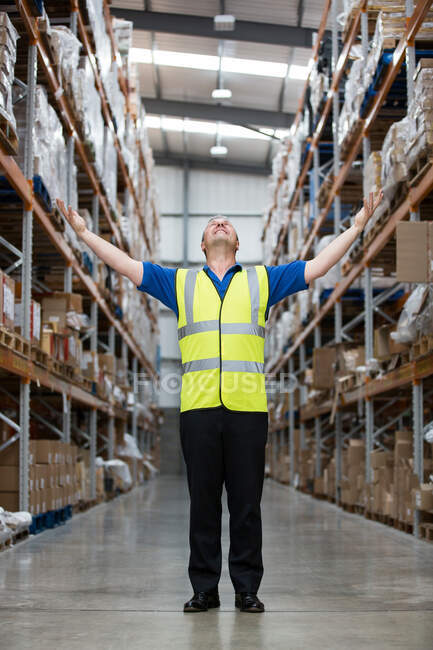 Man with arms raised in warehouse, portrait — Stock Photo