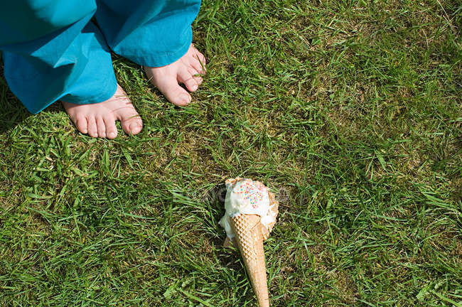 Feet of child and dropped ice cream — Stock Photo