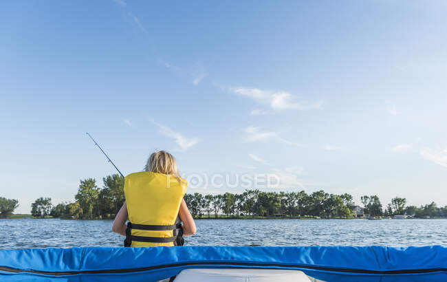 Rear view of boy wearing life jacket fishing — Stock Photo