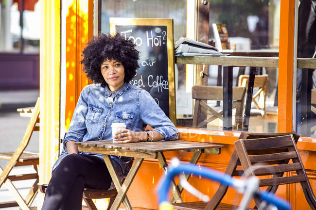 Mulher madura bebendo café takeaway e café calçada — Fotografia de Stock