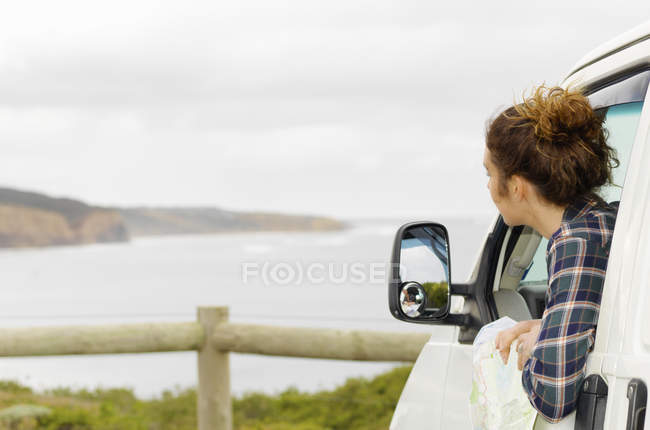 Jovem mulher olhando para fora da janela van campista, Point Addis, Anglesea, Victoria, Austrália — Fotografia de Stock