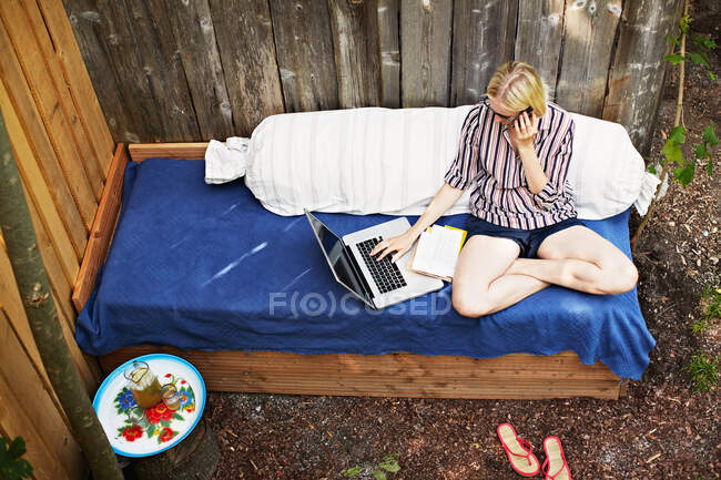 Frau benutzt Laptop auf Sofa im Freien — Stockfoto