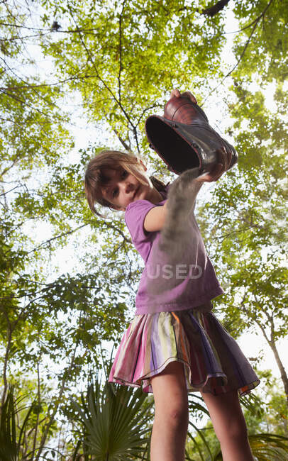 Chica vaciando polvo de bota wellington - foto de stock