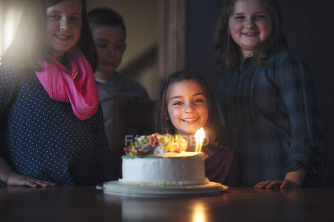 Chica con pastel de cumpleaños rodeado de amigos - foto de stock