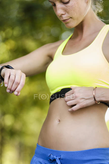 Young female athlete checking heart rate monitors — Stock Photo