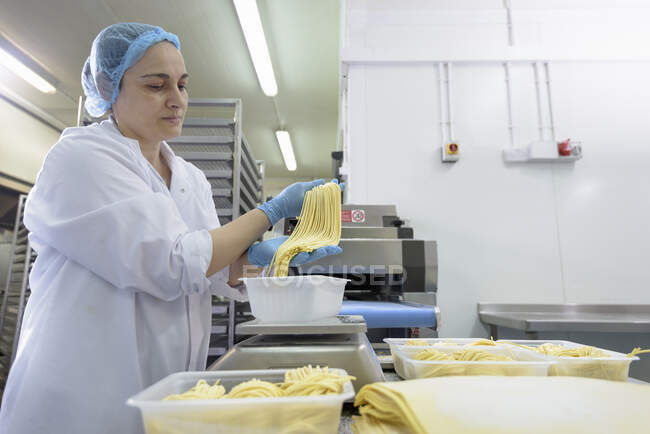 Travailleuse fabriquant des tagliatelles dans une usine de pâtes — Photo de stock