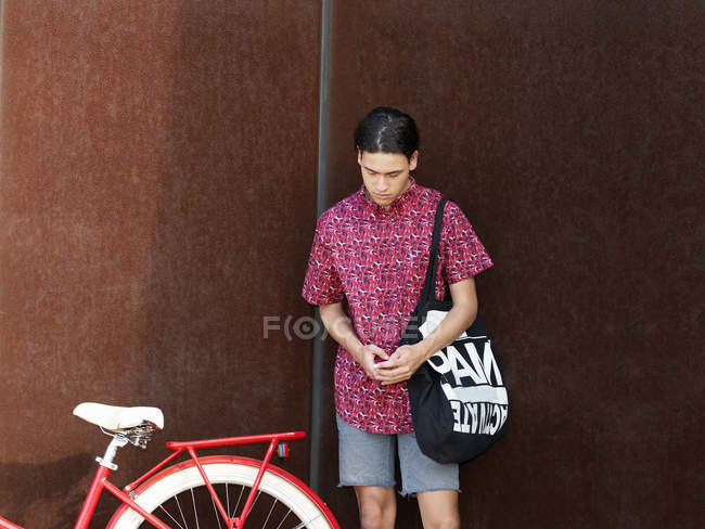 Young man standing beside bicycle — Stock Photo