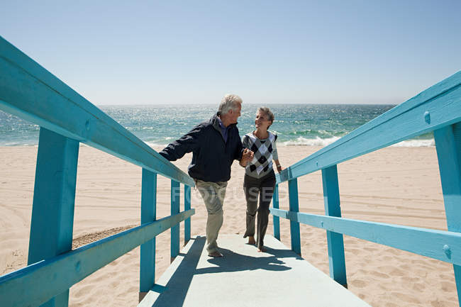 Зрелая пара, идущая по пляжной дорожке — стоковое фото
