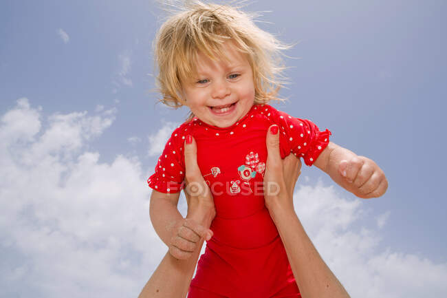 Bebé niña celebrada en el aire - foto de stock