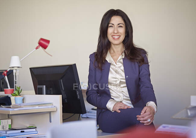 Donna d'affari che indossa un abito seduto alla scrivania — Foto stock