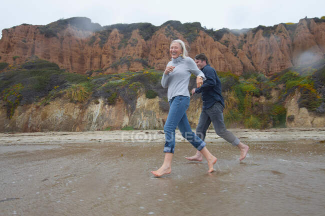 Casal maduro correndo na praia — Fotografia de Stock