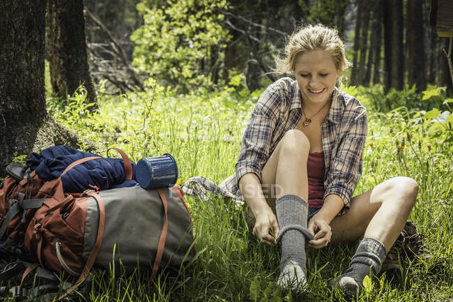 Senderista adolescente que se pone un calcetín en el bosque, Red Lodge, Montana, Estados Unidos - foto de stock