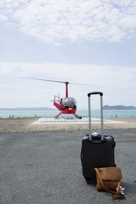Equipaje frente al helicóptero que se prepara para salir de Long Island, Whitsunday Islands, Queensland, Australia - foto de stock