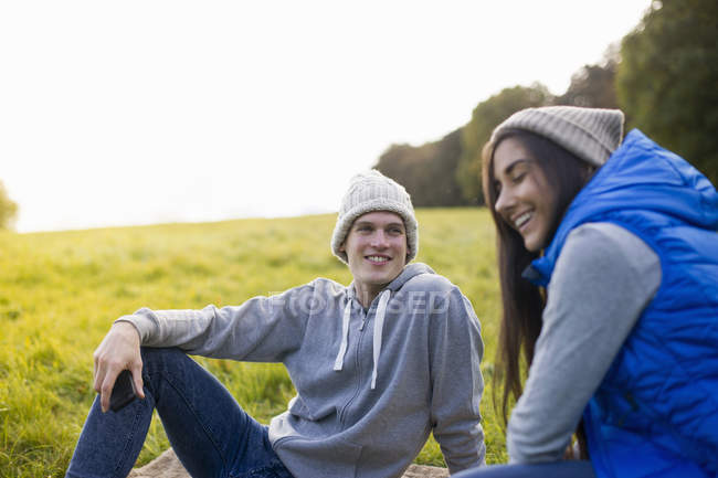Молода пара сидить на траві сміючись — стокове фото