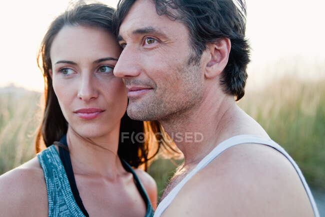 Casal abraçando olhando ao redor na praia — Fotografia de Stock