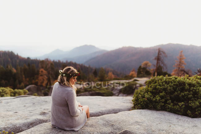 Rückansicht einer Frau, die auf Felsen in Bergen sitzt, Mammutbaum-Nationalpark, Kalifornien, USA — Stockfoto