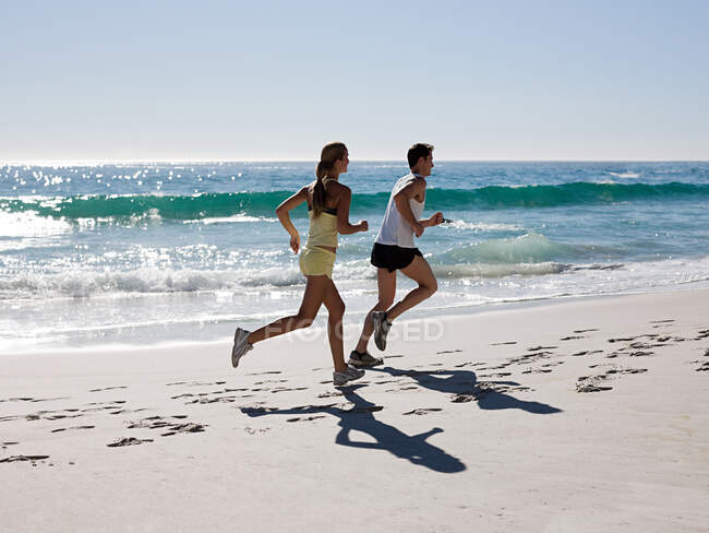 Jeune couple jogging sur la plage — Photo de stock