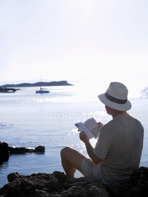 Людина, що читає книжку на березі океану, Дубровник, Хорватія. — стокове фото