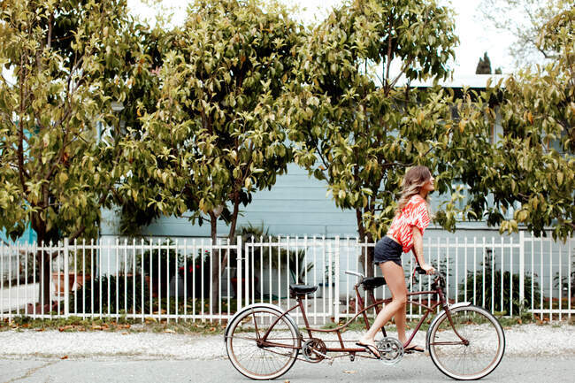 Young woman cycling alone on tandem bicycle along street — Stock Photo