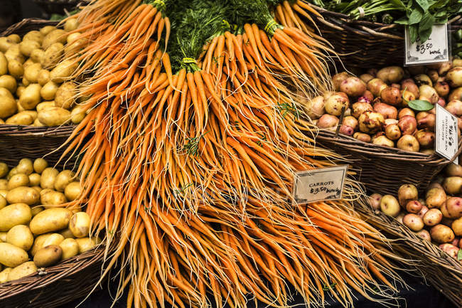 Морковь и картофель в корзинах для продажи на рынке — стоковое фото