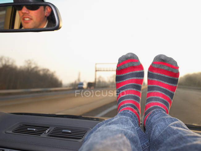 Pies en el salpicadero, mujer y hombre viajando en coche - foto de stock