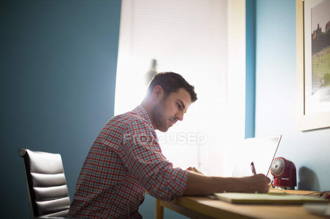 Homem sentado na mesa escrevendo — Fotografia de Stock