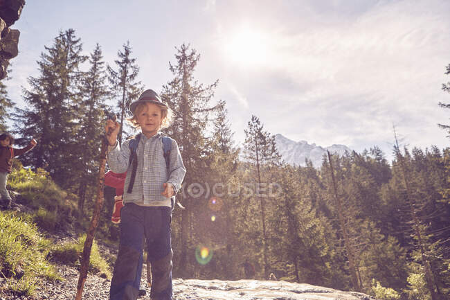 Retrato de un niño parado en la roca, en el bosque - foto de stock