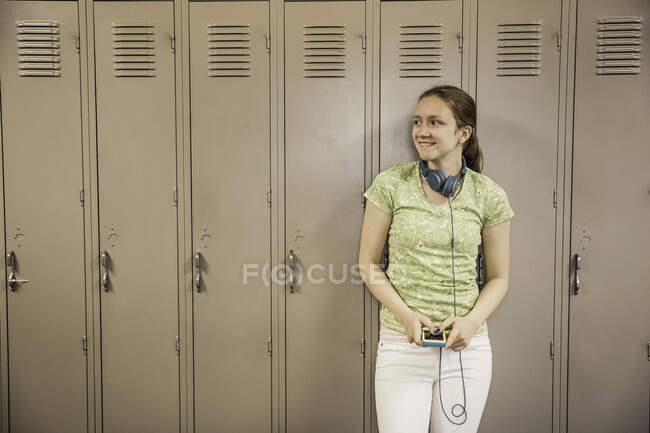 Teenage girl leaning against lockers in high school — Stock Photo