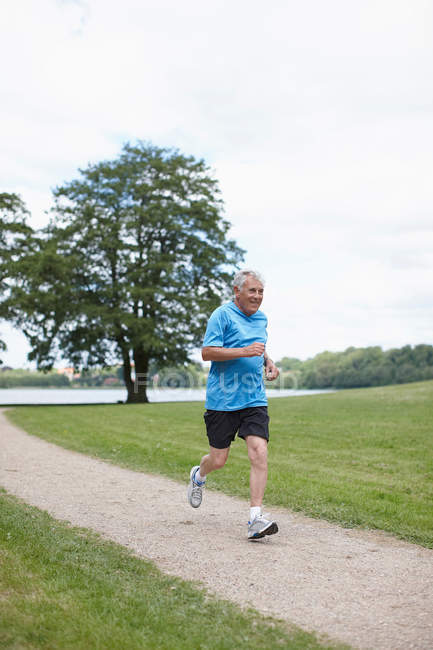 Uomo più vecchio che fa jogging sul sentiero sterrato — Foto stock