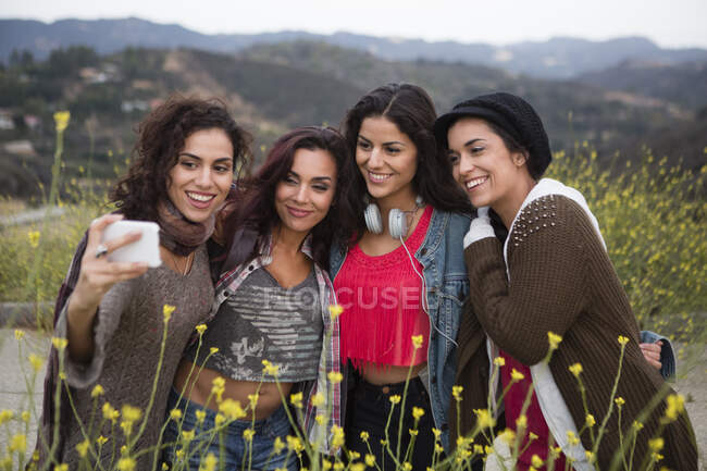 Four adult sisters posing for smartphone selfie on rural road — Stock Photo