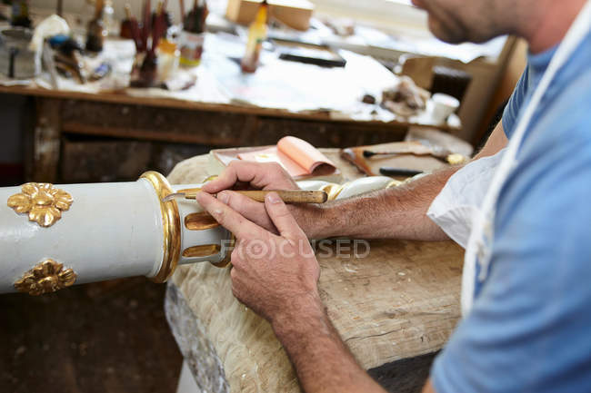 Trabajador aplicando pan de oro al poste - foto de stock