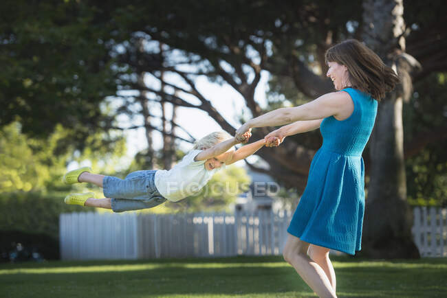 Mãe balançando filho ao redor, ao ar livre — Fotografia de Stock