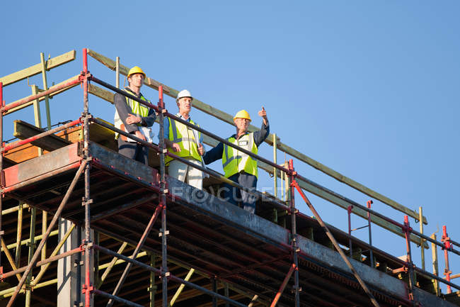 Trabajadores de pie en andamios en el sitio - foto de stock