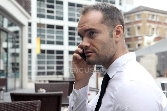 Businessman on cell phone at cafe — Stock Photo