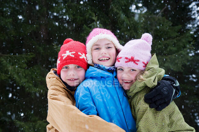 Crianças abraçando na neve — Fotografia de Stock