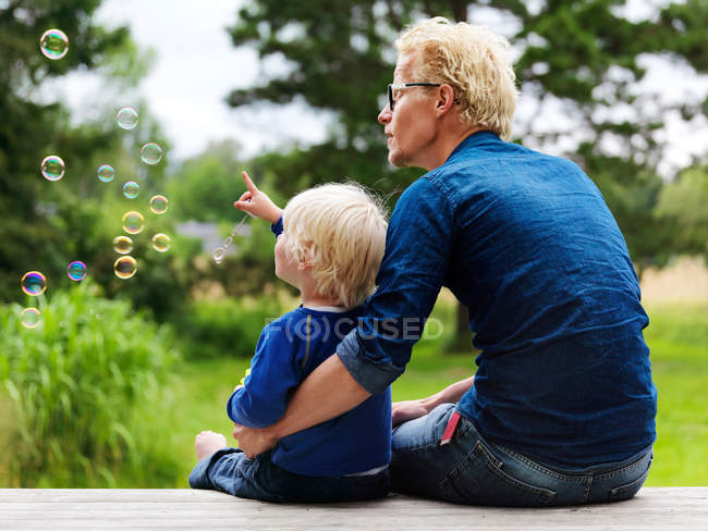Father and son admiring bubbles outdoors — Stock Photo