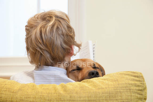 Boy reading and cuddling dog — Stock Photo