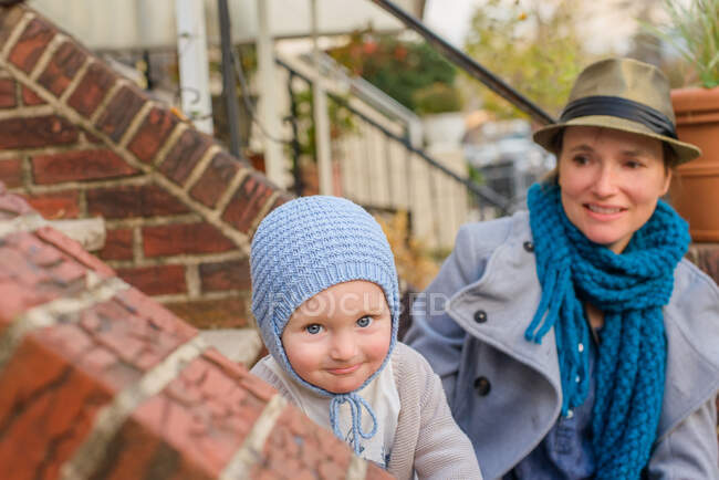 Madre e hijo pequeño sentados juntos en las escaleras delanteras - foto de stock