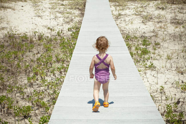 Petite fille sur la promenade sur la plage — Photo de stock
