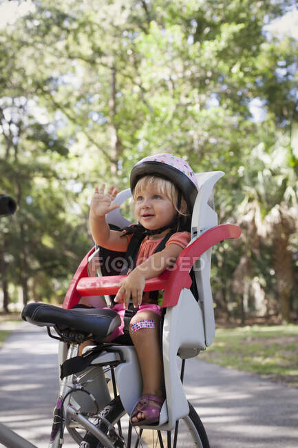 Jeune fille assise dans le siège de vélo de l'enfant, profiter du voyage — Photo de stock
