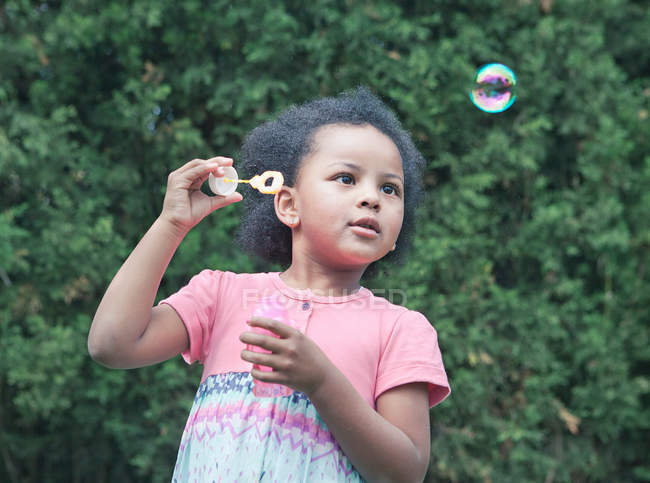 Fille soufflant des bulles à l'extérieur — Photo de stock