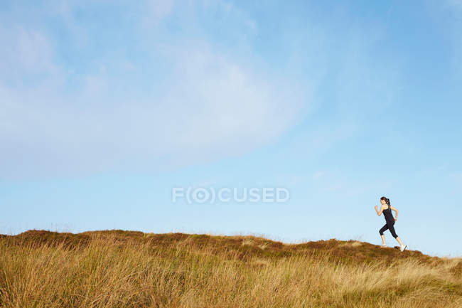 Жінка біжить на сільському схилі пагорба — стокове фото