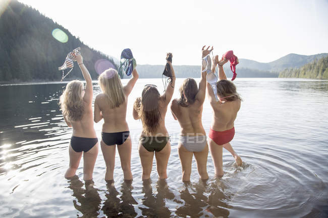 Visão traseira de mulheres jovens decolando biquínis tops, Lost Lake, Oregon, EUA — Fotografia de Stock