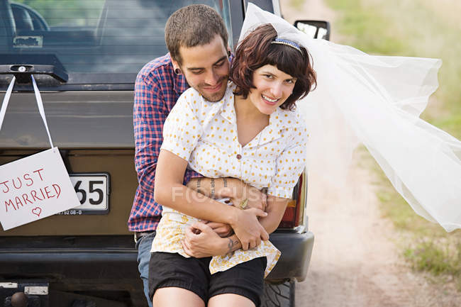 Newlywed couple by vehicle — Stock Photo